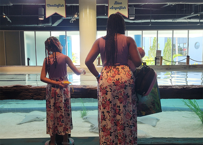 mom and daughter in matching dresses with purple top and floral skirt in front of the stingray touch experience