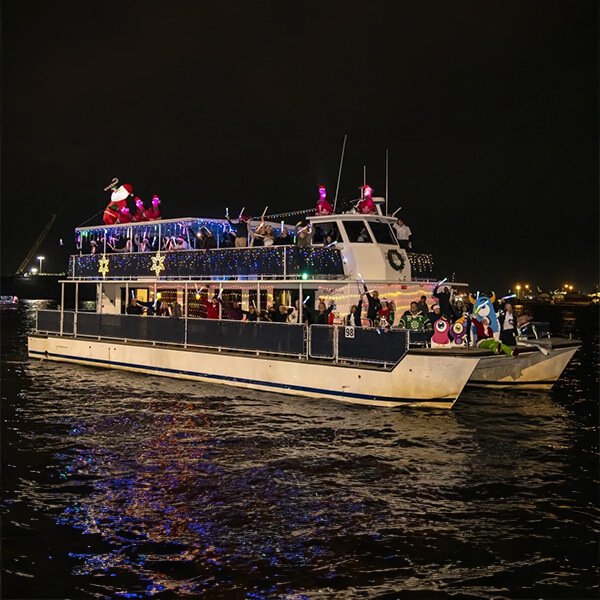 people on boat with holiday lights on the water