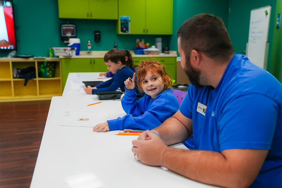 little girl smiling at learning team member